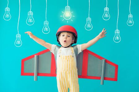 Happy child playing with toy paper wings against blueの写真素材