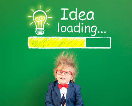 Bright idea! Funny child student in class. Happy kid against green chalkboard. Online education and e-learning concept. Back to schoolの写真素材