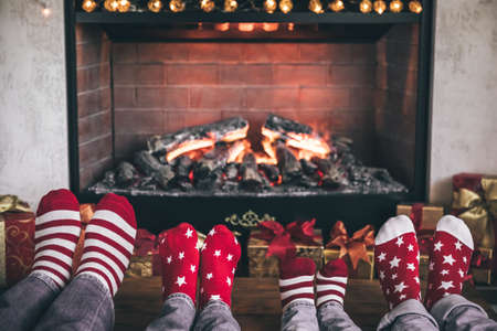 Happy family with children near fireplace at Christmas. Feet wearing Xmas socks. Winter holiday conceptの写真素材