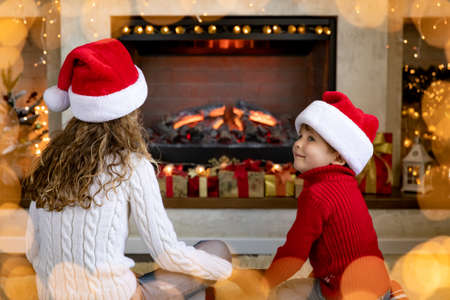 Happy children near fireplace at Christmas. Kids having fun at home. Xmas holiday conceptの写真素材