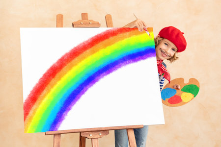 Happy child painting rainbow at home. Imagination and childhood dream concept