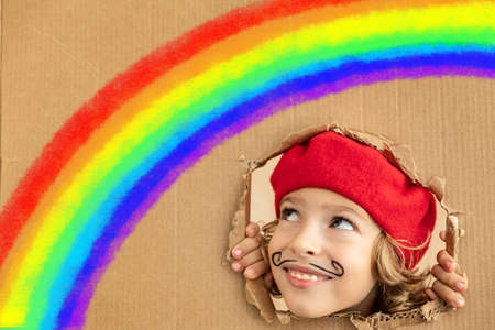 Happy child painting rainbow at home. Imagination and childhood dream conceptの写真素材