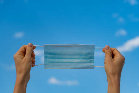 Protection medical mask outdoor against blue sky background. Person enjoying by sea at summer.の写真素材