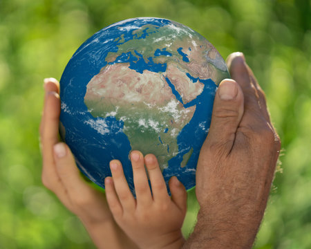 Family holding 3D planet in hands against green blurred background. Earth day spring holiday...