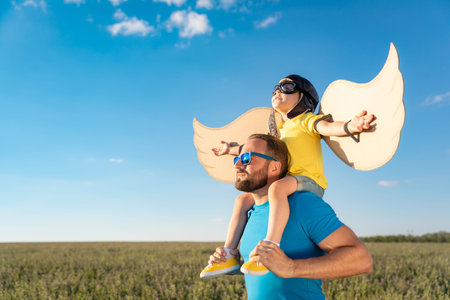 Happy family having fun outdoor. Father and son playing against blue summer sky background....