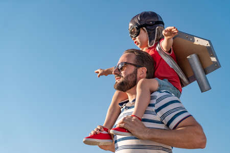 Happy family having fun outdoor. Father and son playing against blue summer sky background. Imagination and freedom conceptの写真素材