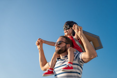 Happy family having fun outdoor. Father and son playing against blue summer sky background....