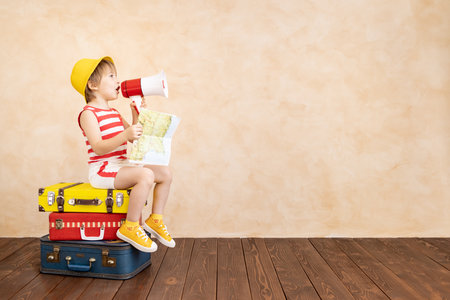Happy child playing at home. Smiling kid dreaming about summer vacation and travel. Imagination and freedom conceptの写真素材