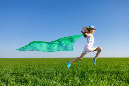 Jump into spring! Cute girl flying in spring field.の写真素材