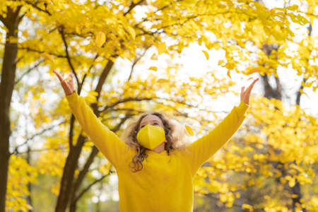 Happy child wearing protective mask outdoor. Girl having fun in  in autumn park.の写真素材