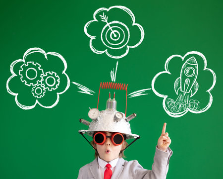 Smart child against green chalkboard. Funny kid wearing helmet with lightbulb. Education, start up...