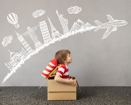 Child playing at home. Kid sitting in cardboard box. Child dreaming about travel. Children...