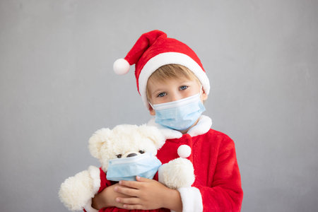 Portrait of child wearing medical mask. Kid holding teddy bear. Christmas holiday during coronavirus covid-19 pandemic conceptの写真素材