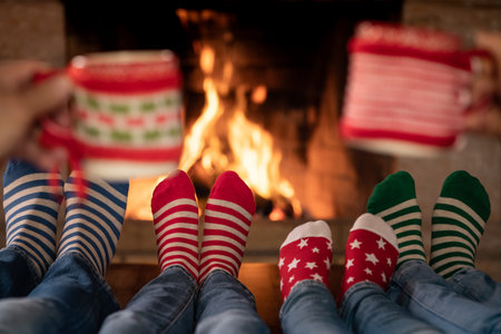 Family in Christmas socks near fireplace. Mother; father and children having fun together. People relaxing at home. Winter holiday Xmas and New Year conceptの写真素材