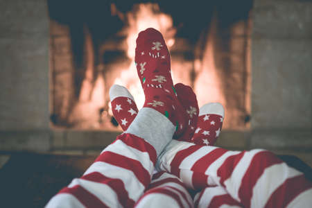 Couple in Christmas socks near fireplace. Man and woman having fun together. People relaxing at home. Winter holiday Xmas and New Year conceptの写真素材
