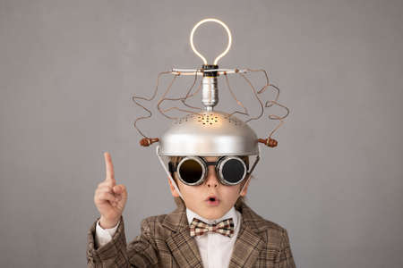 Smart child pretend to be businessman. Funny kid wearing helmet with lightbulb. Education, start up and business idea conceptの写真素材