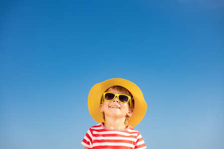 Happy child having fun outdoor against blue sky background. Portrait of smiling kid on summer vacation. Freedom and travel conceptの写真素材