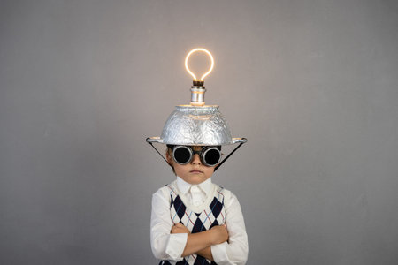 Smart child pretend to be businessman. Funny kid wearing helmet with lightbulb. Education, start up and business idea conceptの写真素材