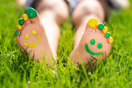 Happy child with smile on feet outdoor. Kid lying on green spring grass. Ecology and healthy lifestyle conceptの写真素材