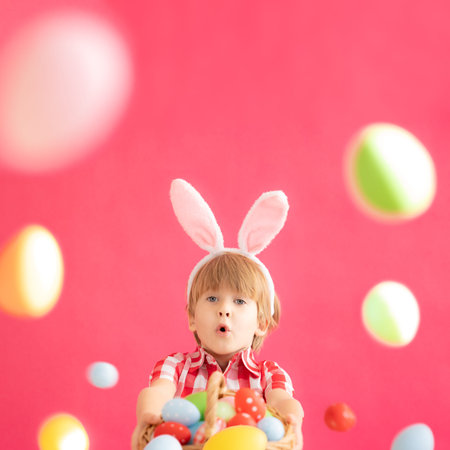 Surprised child holding basket with Easter eggs. Funny kid wearing Easter bunny. Child having fun at...