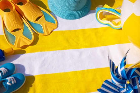 Beach accessories on yellow striped towel. Summer vacation conceptの写真素材