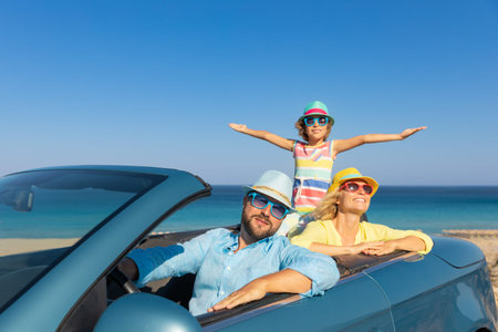 Happy family travel by car at the sea. Mother, father and daughter having fun in blue cabriolet....