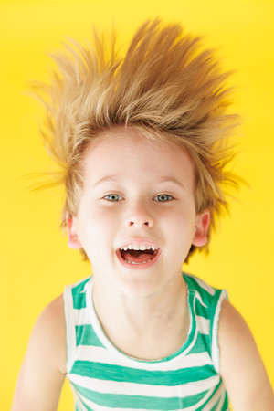 Happy child shouting against yellow paper background. Funny kid hanging upside down. Summer vacation and travel conceptの写真素材