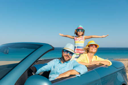 Happy family travel by car at the sea. Mother, father and daughter having fun in blue cabriolet. Summer vacation conceptの写真素材
