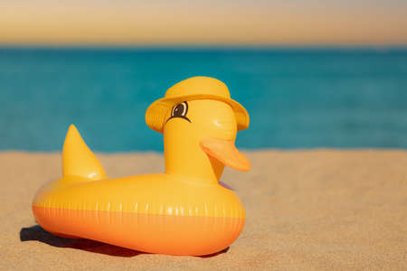 Funny yellow duck wearing beach hat against blue sea and sky background. Summer vacation and travel conceptの写真素材