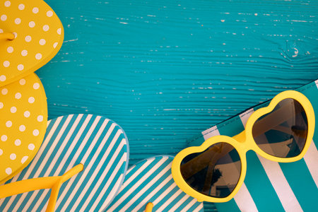 Beach flip-flops and sunglasses on blue wooden background. Summer vacation and travel concept...
