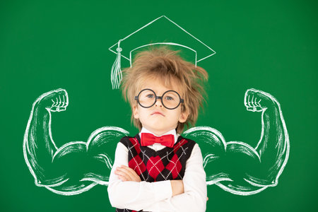 Funny child student in class. Happy kid against green chalkboard. Education concept. Back to school