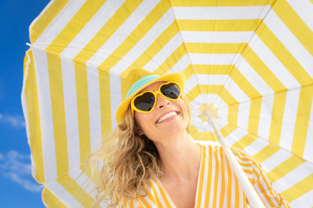 Beautiful woman on summer vacation. Low angle view portrait of happy person against blue sky...