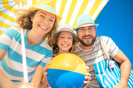 Happy family on summer vacation. Low angle view portrait of happy people against blue sky backgroundの写真素材
