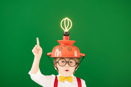Smart child in the class against blackboard. Funny kid with lightbulb at school. Education, start up...