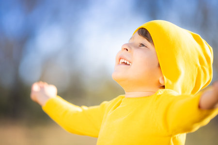 Portrait of happy child against yellow leaves background. Smiling kid having fun outdoor in autumn park. Freedom and imagination conceptの写真素材