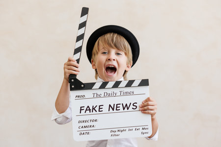 Director shouting against grunge wall background. Boy playing in home. Child wearing vintage costume. Kid holding clapper. Social media and Internet nerwork conceptの写真素材