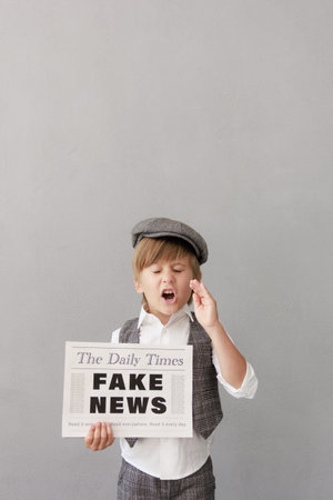 Newsboy shouting against grunge wall background. Boy selling fake news. Child wearing vintage...
