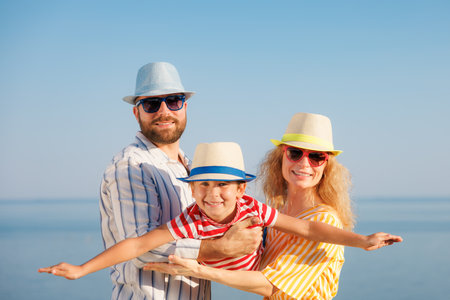Happy family having fun on summer vacation. People playing outdoor. Mother, father and child against blue sea and sky backgroundの写真素材