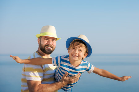 Happy family having fun on summer vacation. father and child together. Dad and son against blue sea and sky background. fathers day conceptの写真素材
