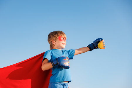Superhero child against summer blue sky. Super hero boy having fun outddor. healthy lifestyle conceptの写真素材
