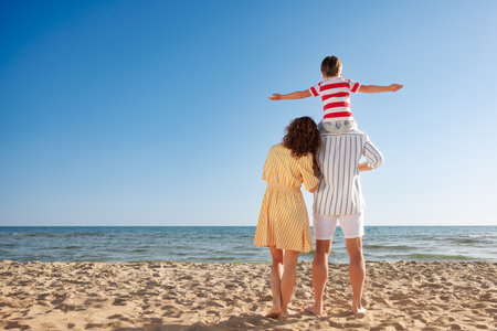Happy family on summer holiday. Mother, father and child having fun on the beach. Summer vacation and travel concept. full length portrait; rear viewの写真素材
