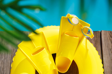 Fippers and goggles on wooden background. Things for vacation against blue water of swimming pool. Summer holiday and travel conceptの写真素材