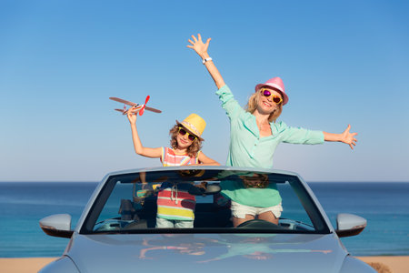 Happy family travel by car by the sea. Mother and child having fun in blue cabriolet. Summer vacation conceptの写真素材