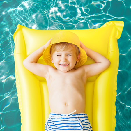 Happy child having fun on summer vacation. Funny kid playing in swimming pool. Active healthy...