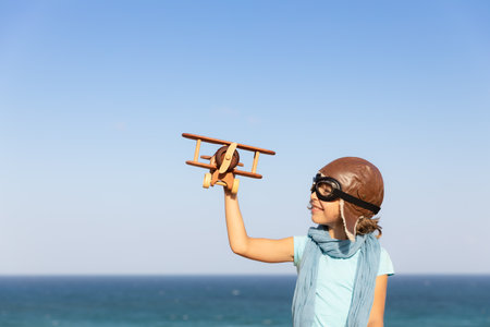 Happy child playing with vintage wooden airplane at the beach. Kid having fun on summer vacation. Imagination and freedom conceptの写真素材