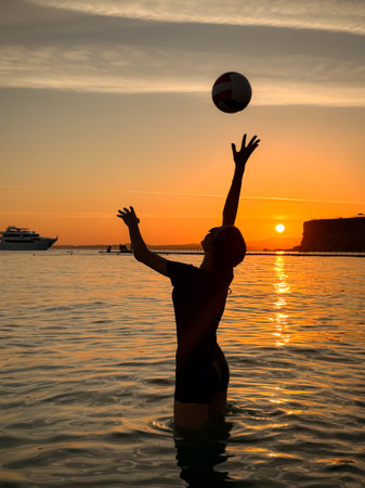 Silhouette of young girl playing volleyball at the beach.