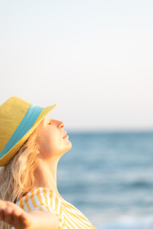 Young happy woman enjoying by sunrise against blue sky background. Female walking along the beach on summer vacationの写真素材