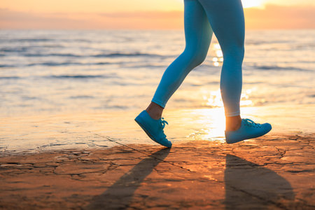 Sporty young woman is running against sea background. Female doing workout and cardio. Wellness,...