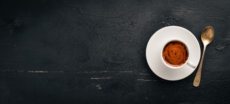 A cup of espresso coffee on a dark wooden background. Top view. Free space for text.の写真素材