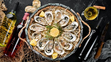 Fresh oysters with lemon in Wooden Box. On a black stone background. Top view. Free copy space.の写真素材